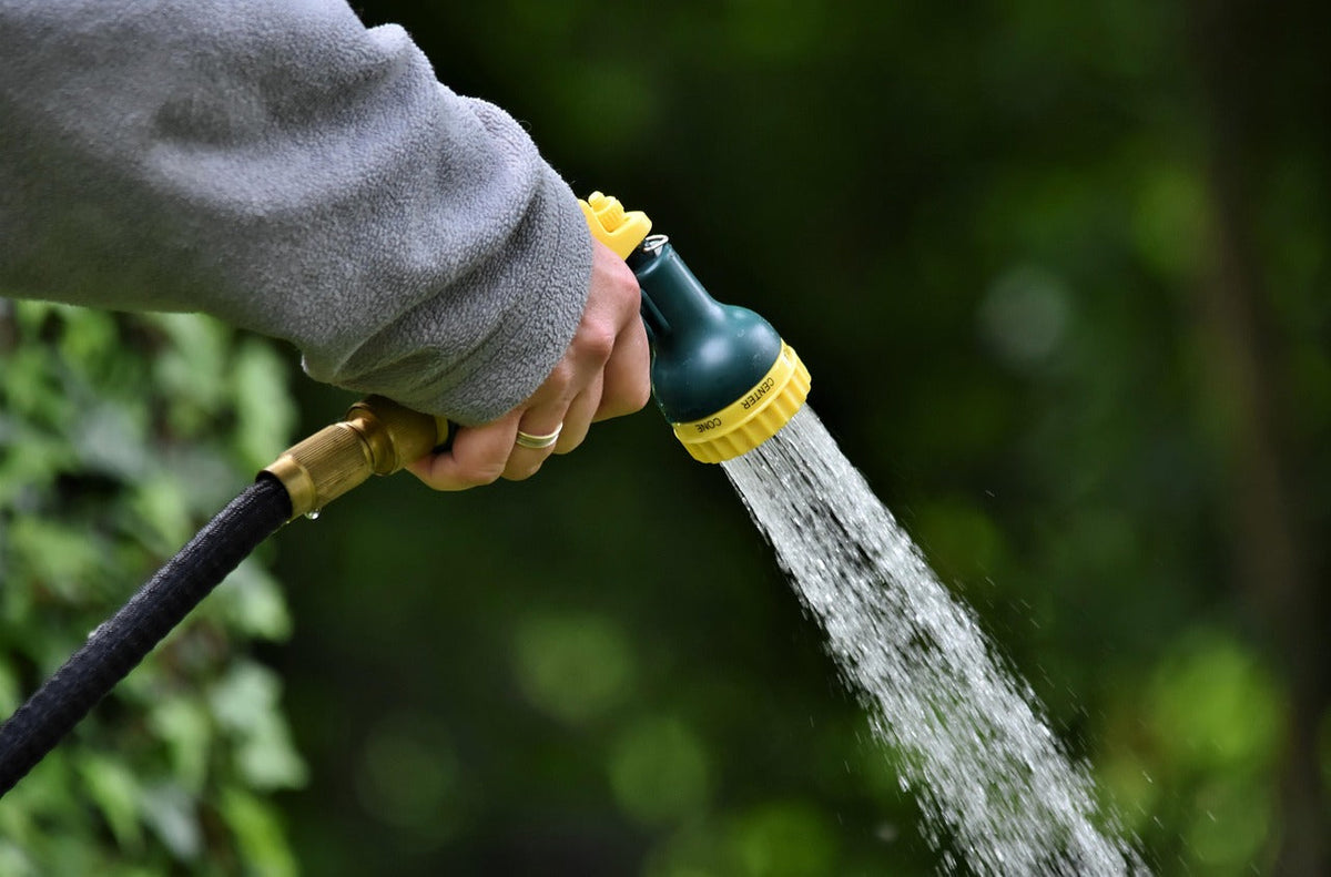 Hand mit Gartenschlauch aus dem Wasser kommt